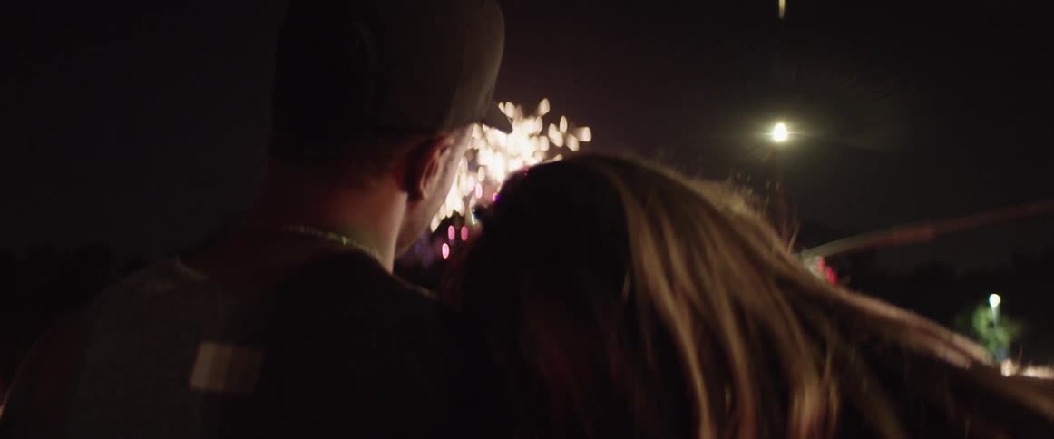 Young couple watch a firework show from the street of a small town