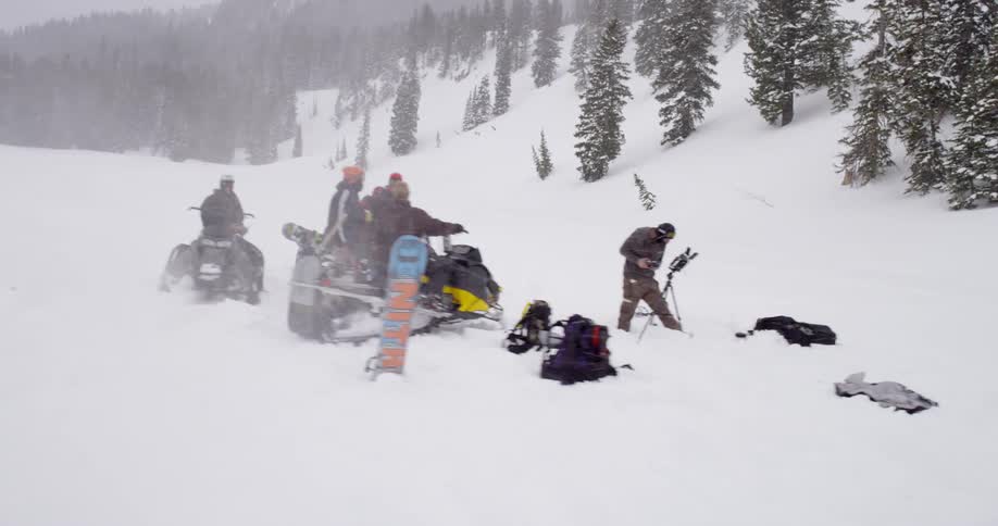People gather around snowmobiles on a snowy day