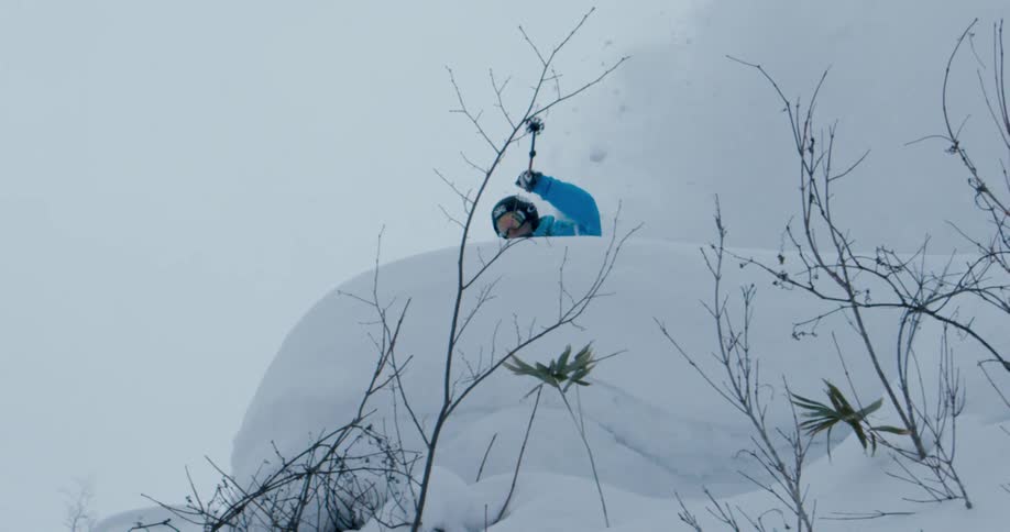 A skier leaps off a cliff and sends snow flying down below