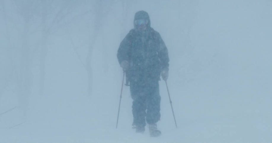 A skier hiking through snow in a winter blizzard