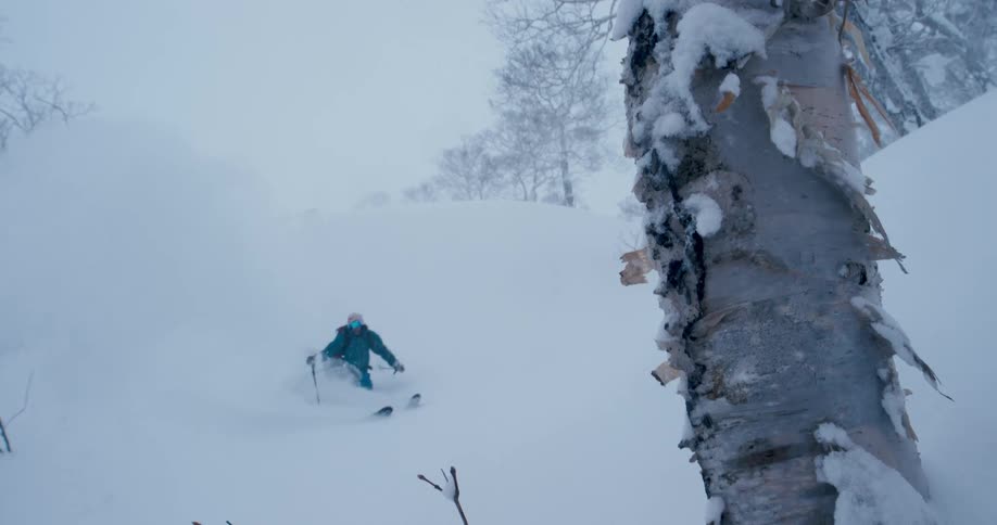 A skier glides down a snowy mountainside on a winter day
