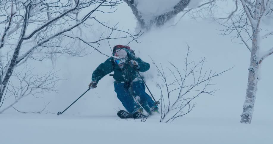 Snow sprays up as a man skis down a hill