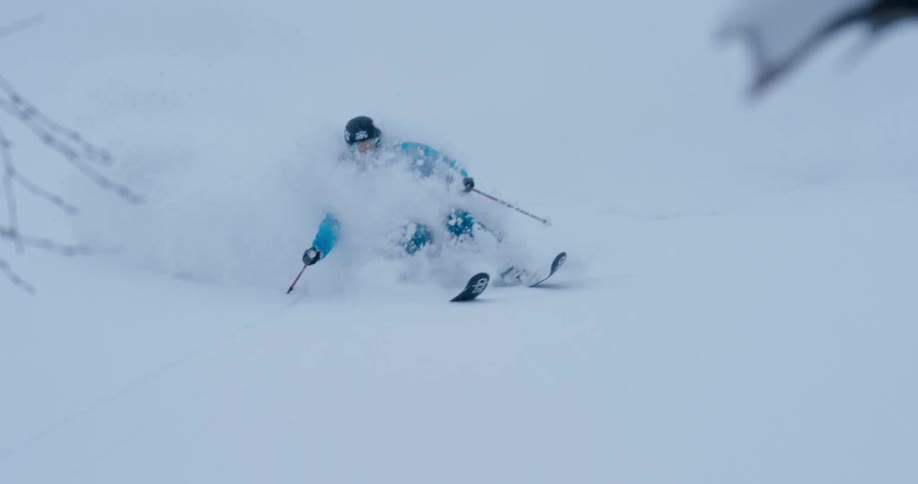 A skier tries to maintain balance while going down a slope with deep snow