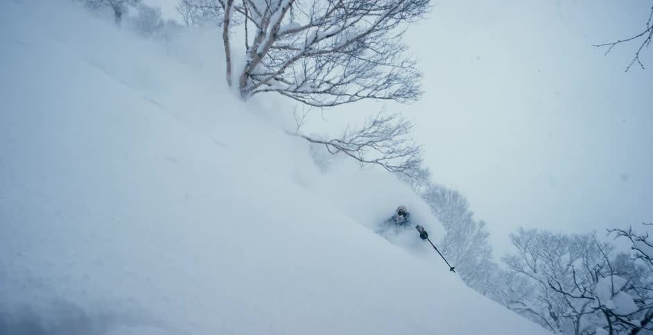 Snow flies as a person skis down a hill