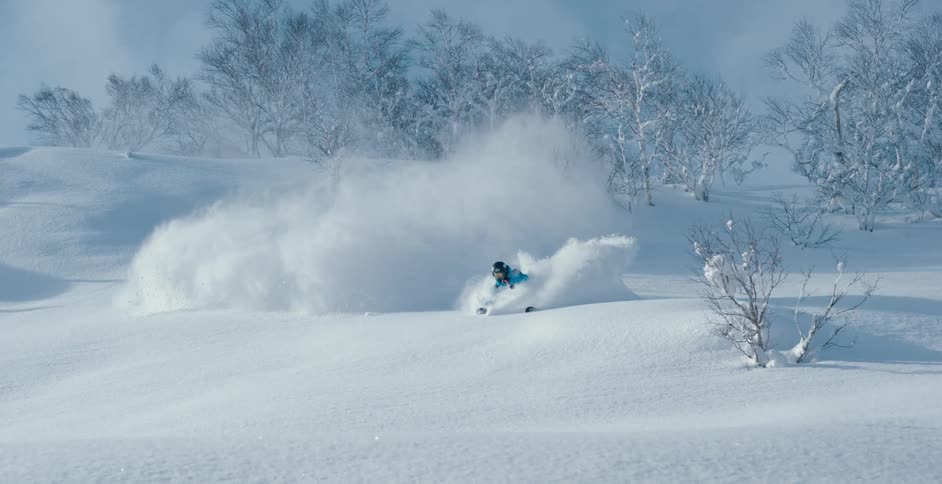 A skier falls and twists while coming down a curved slope