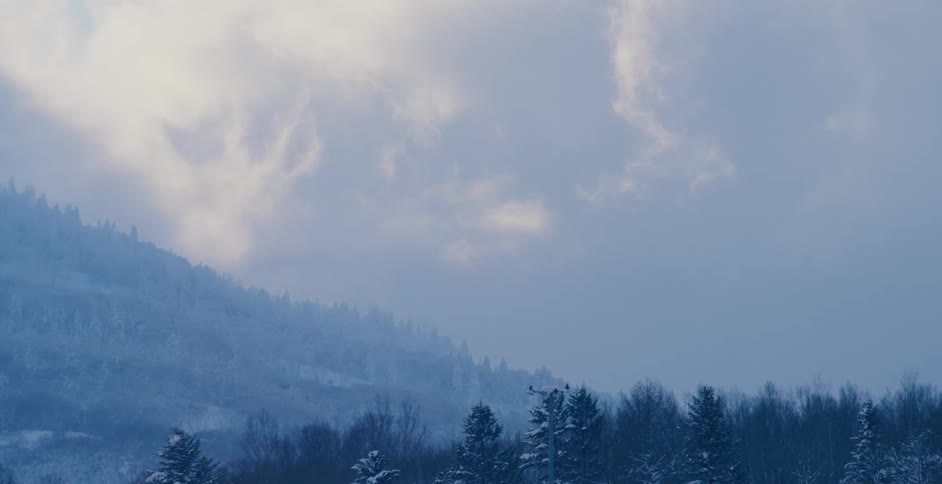 Thick clouds and fog cover mountain slope and forest