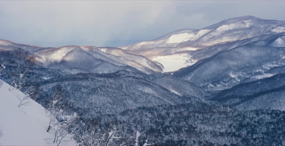 Light snowfall over the trees in the hills and mountains at morning