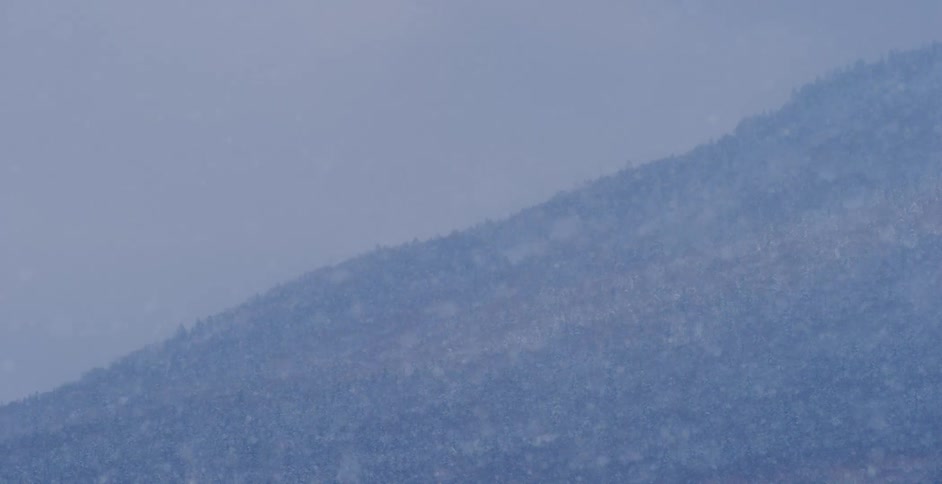 Blowing snowflakes obscure mountain slope