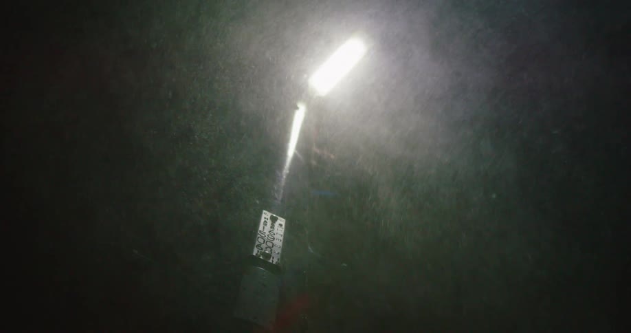Snow blowing around an illuminated street lamp during a blizzard at night