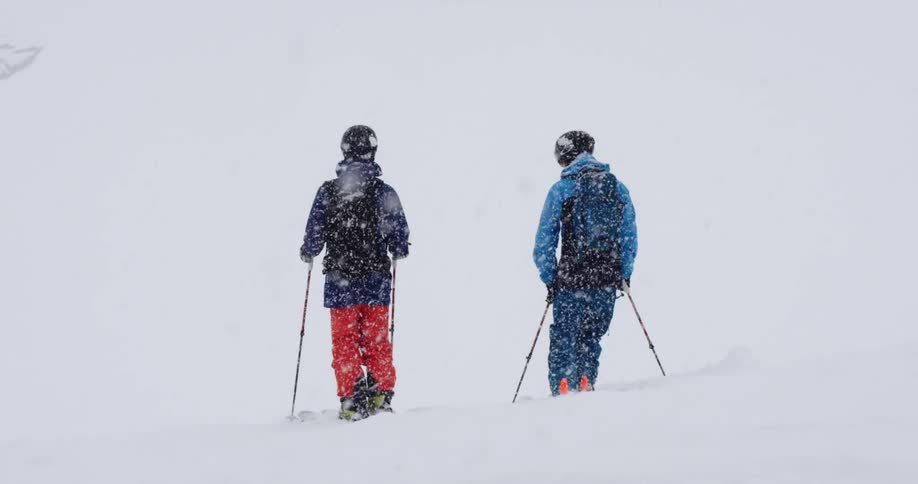Two people have ski equipment and are standing outdoors