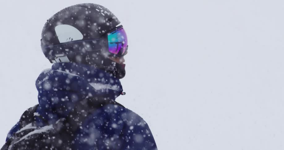 A man is standing outdoors in winter while wearing ski equipment