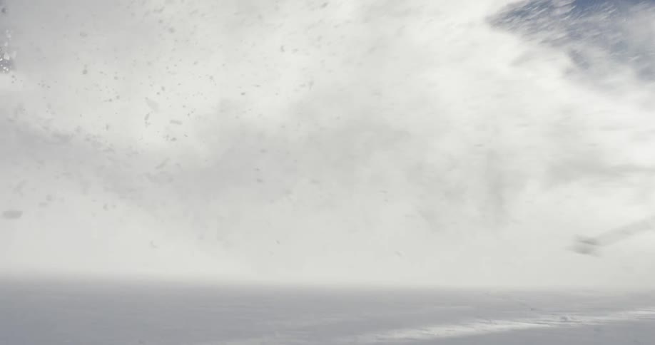 A skier in a blue coat gliding down a snowy mountainside on a winter day