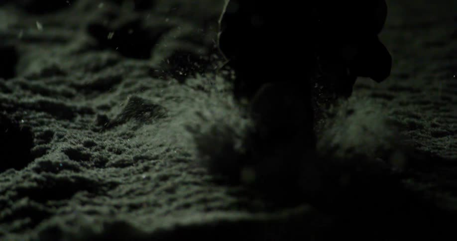 A man is walking through the snow at night
