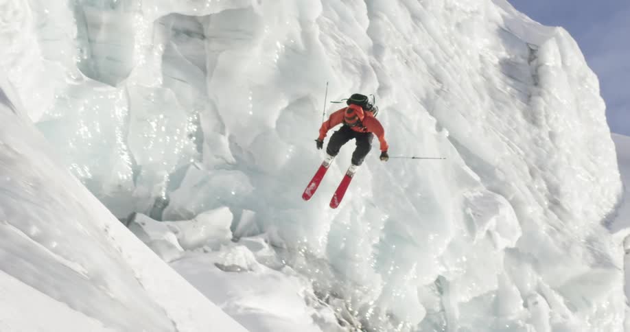 A person skiing down a mountain jumps and turns in mid air