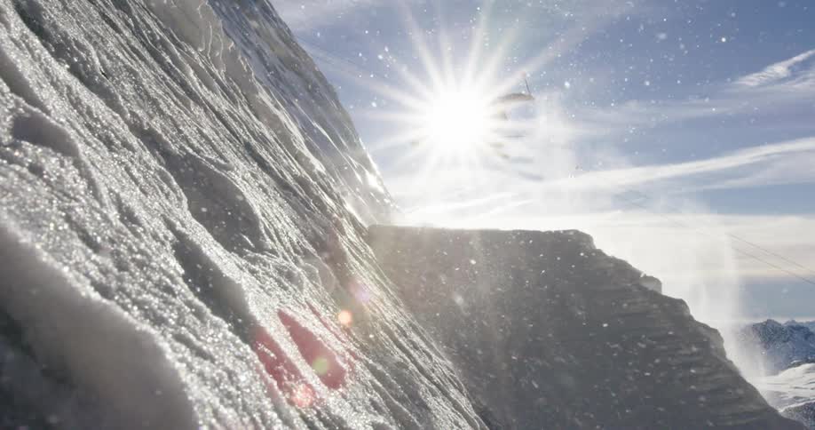 Sunlight illuminates skier jumping a ramp on the slope of a snow covered mountain