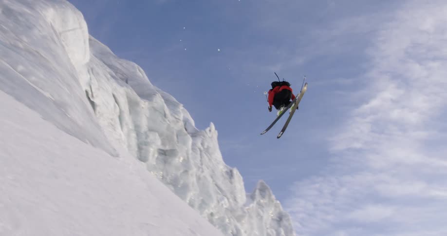 A person is skiing down a mountain at midday