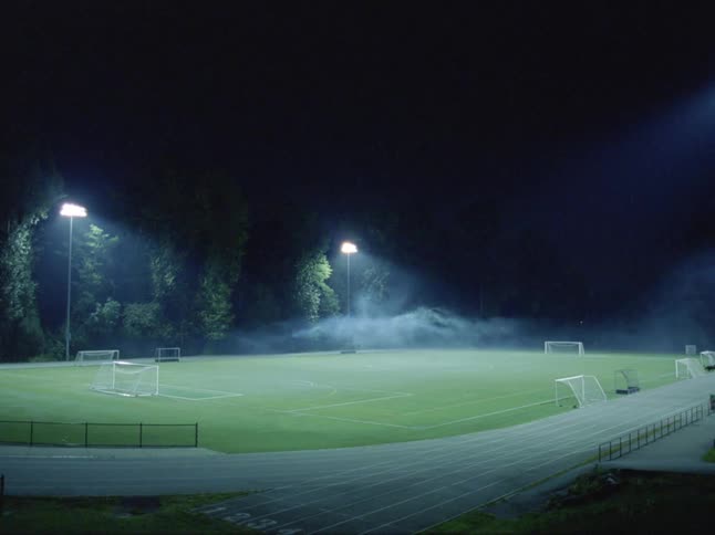 Fog rests just above a soccer field in a track and field outdoor stadium