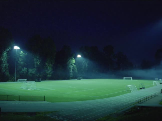 Lights shining down on a soccer field on a summer night