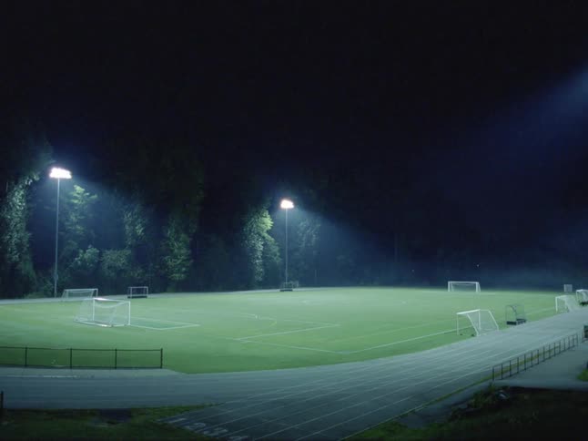 A soccer field with lights and trees in the background