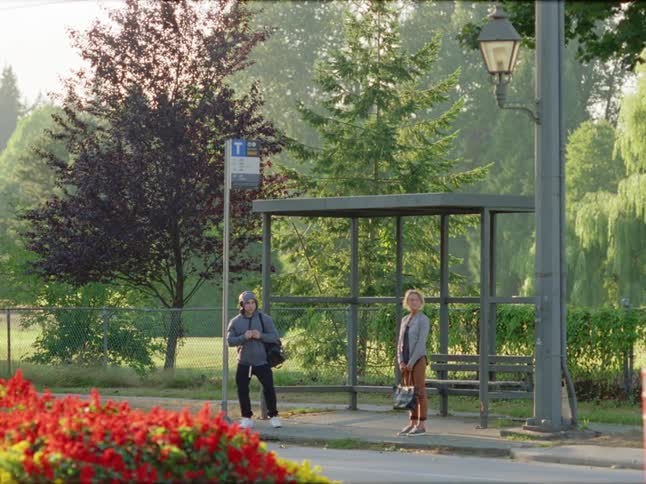 Manwith a backpack and blonde woman holding a handbag stand at the bus stop
