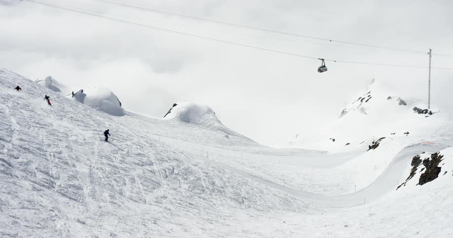 Skiers on a ski lift and skiing down a snowy mountain