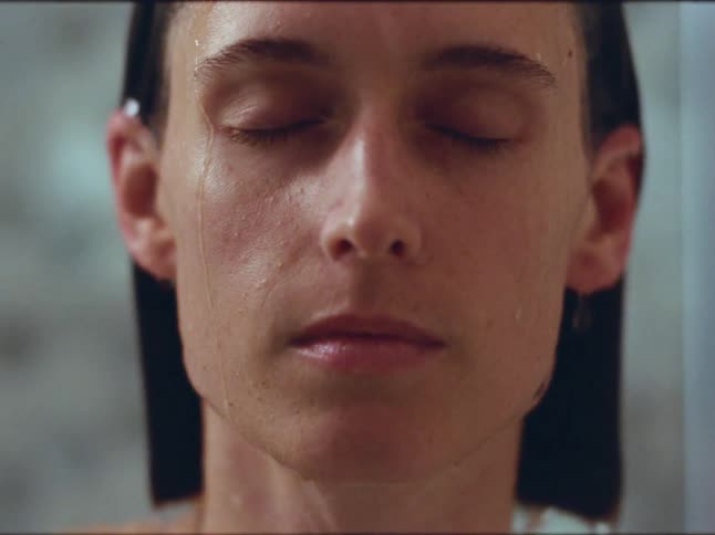 Woman having a shower with eyes closed opens her eyes and stares at the camera