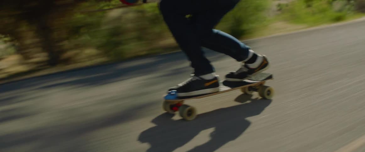 A person rides a skateboard down a rural road