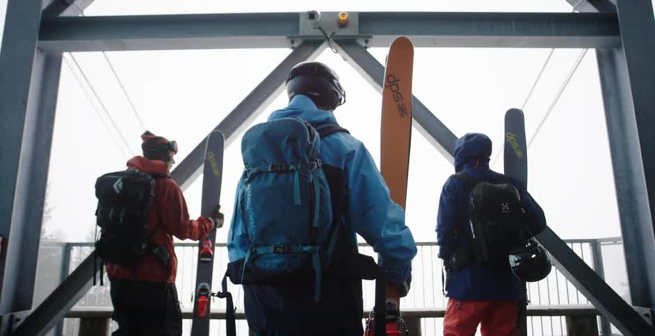 Three people holding skis waiting in a building
