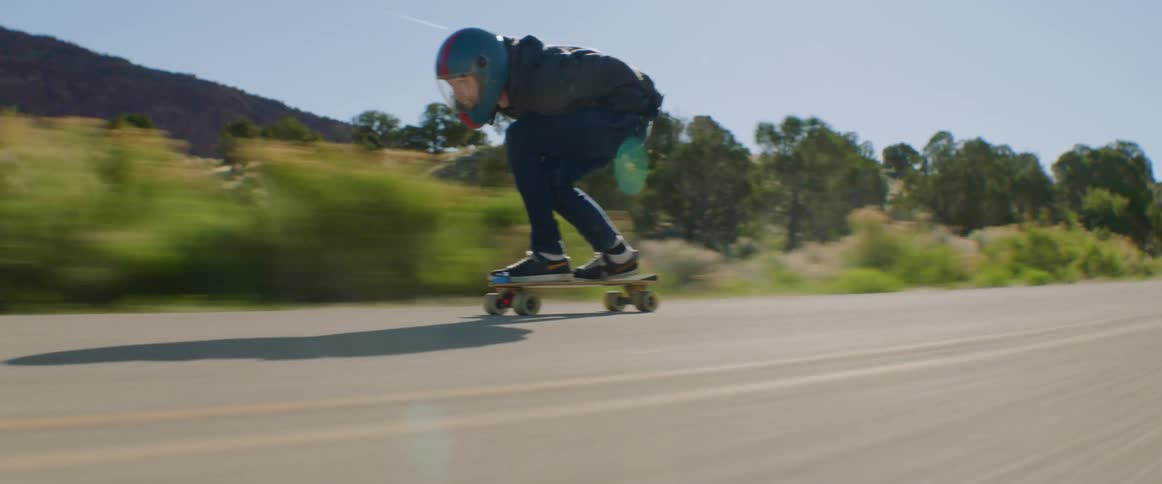 A person skateboards downhill quickly on a quiet road