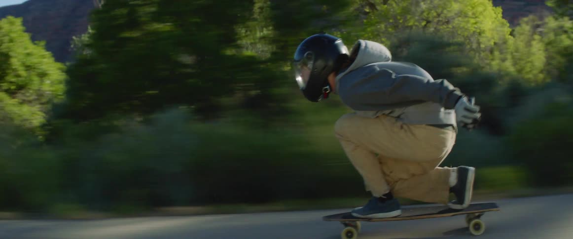 A teenage boy skateboarding down a street