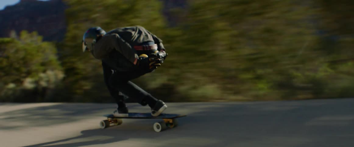 A person skateboards down a quiet rural road