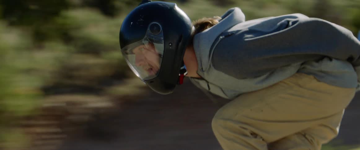People with helmet and gloves skateboarding down a road
