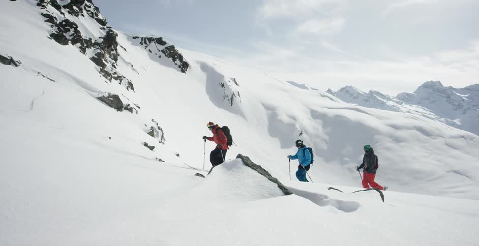 Three skiers climbing up a snow covered mountain