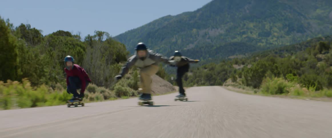 A group of people riding skateboard down a mountain
