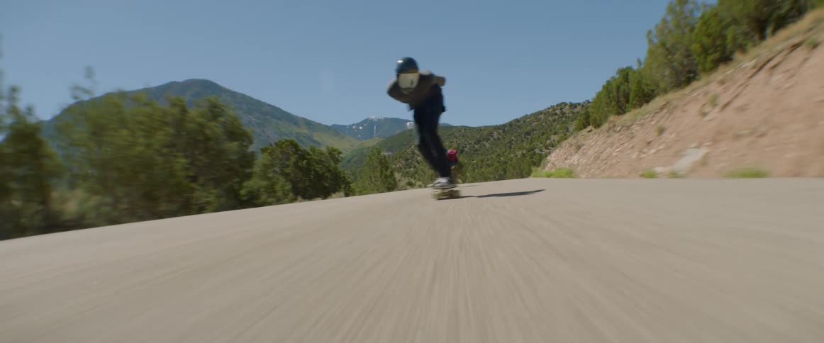 Three teenagers on skateboards riding down empty rural highway