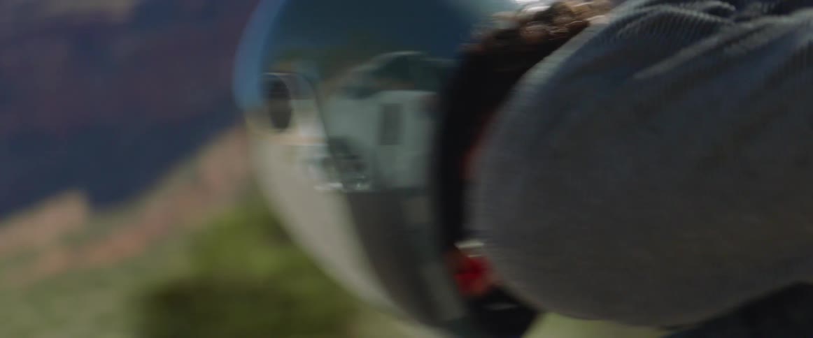 Skateboarders ride skateboards at high speed on a road with mountains in the background