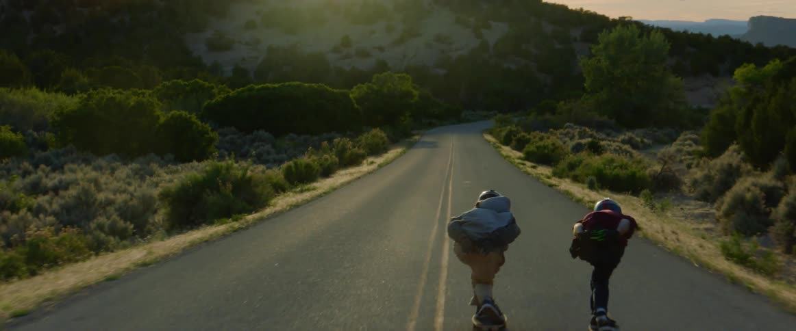 People with helmet and gloves skateboarding down a road
