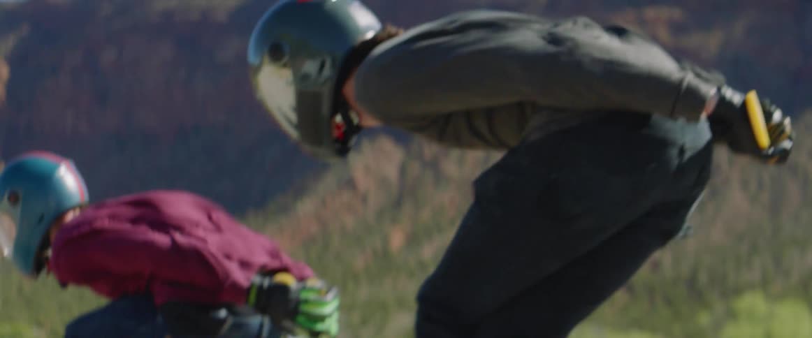 People with helmet and gloves skateboarding down a road