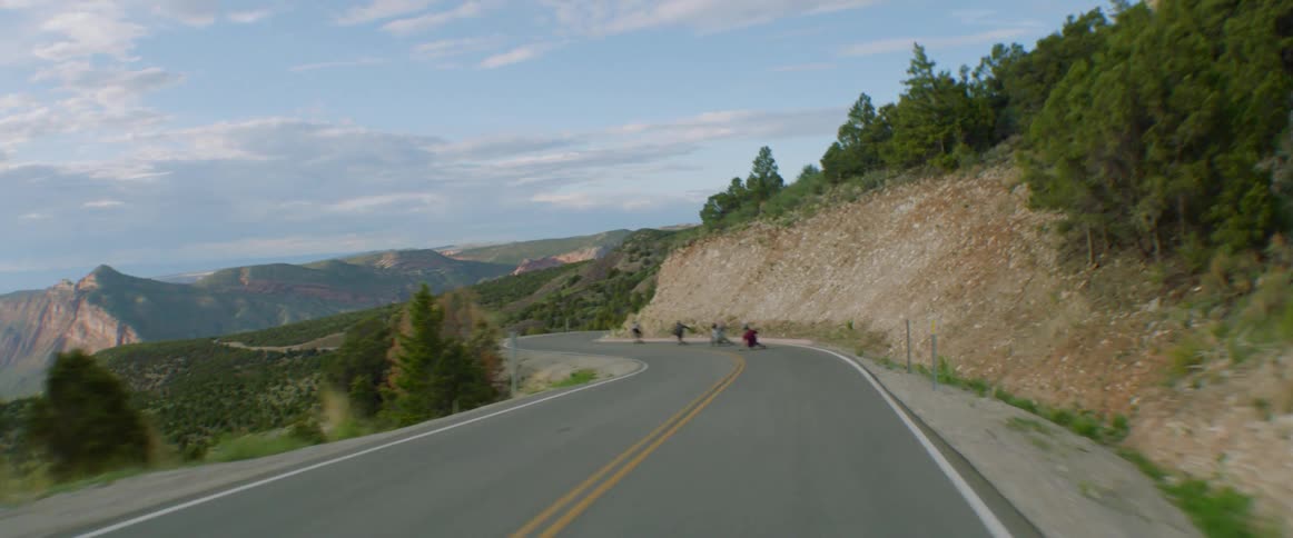 A group of people riding down a mountain on longboards