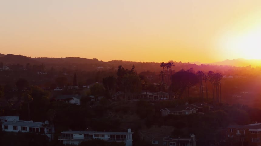The sun is rising on the neighborhood on the hills