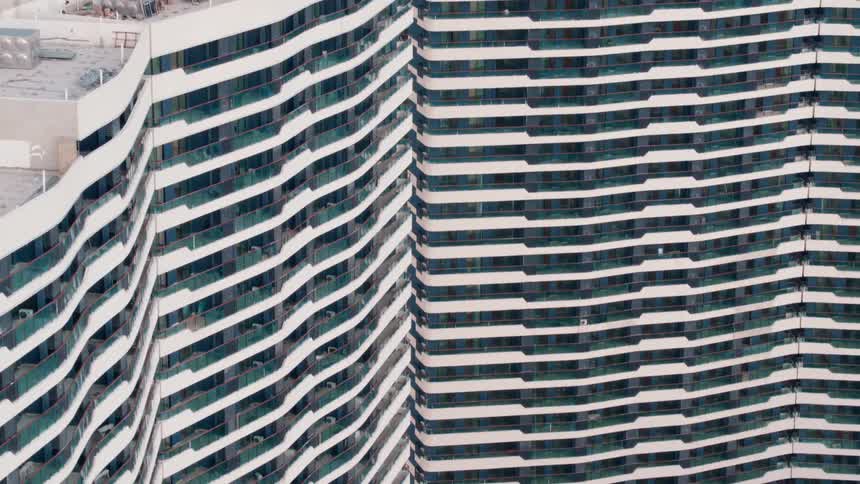 Identical tall white apartment buildings sit next to each other near a lake