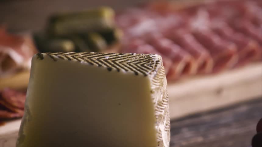 Deli meats and cheese sit on a wood cutting board