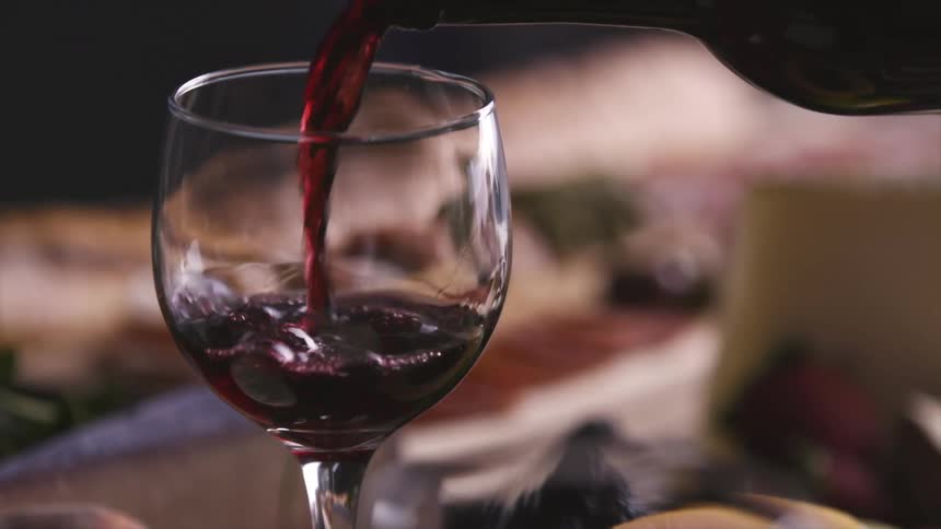 Red wine flows into wine glass near meal