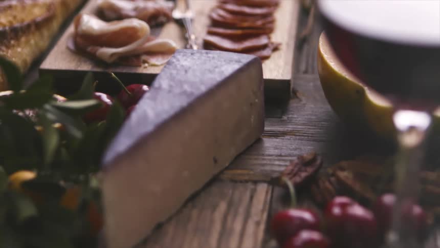 A spread of meat cheese fruit and nuts all laid out on a table