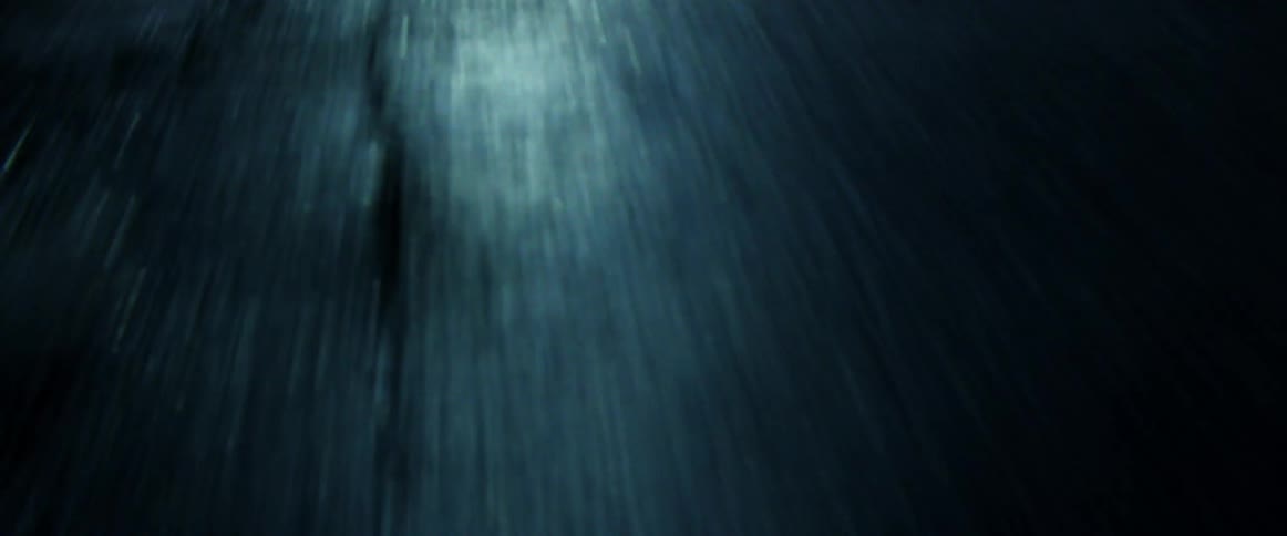 Headlights reflect on a paved road at night