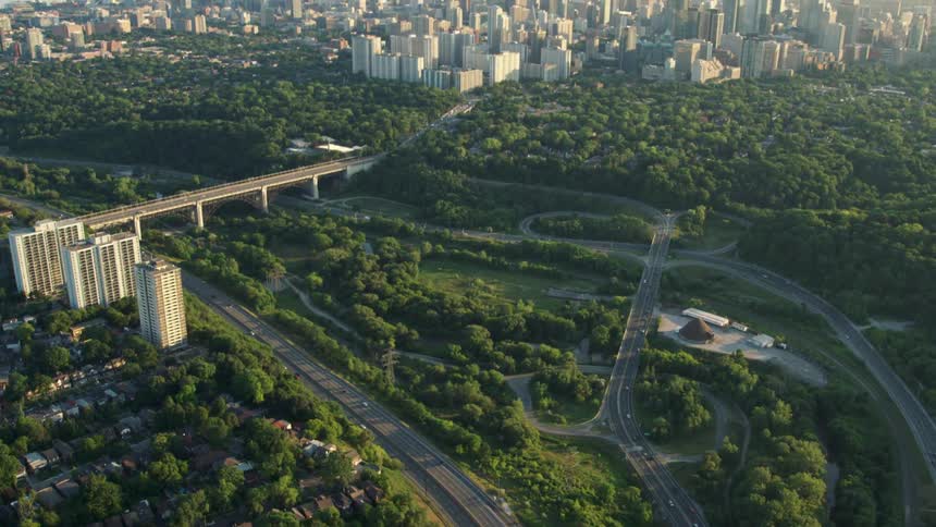 Aerial of a freeway surrounded by trees outside a big city