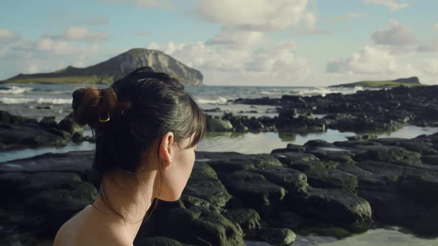 A woman is standing by the beach during the day