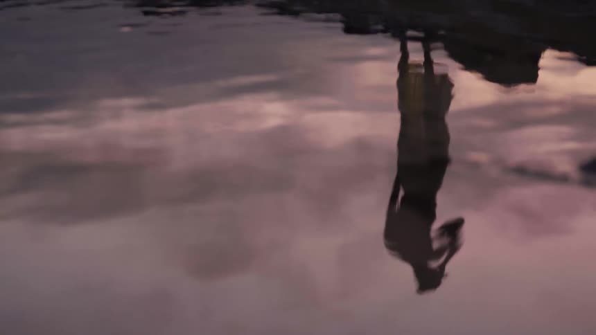A persons shadow is reflected in the lake