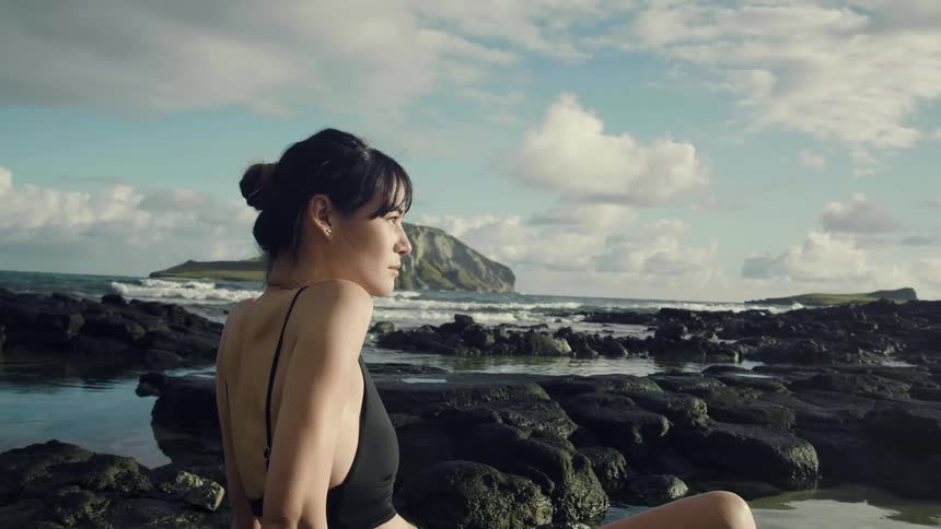 A woman is sitting on the rocks on the beach