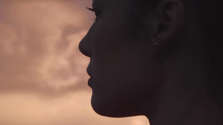 A female side profile who is wearing an earring